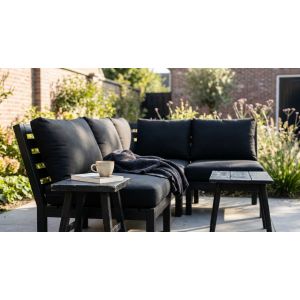 Zwarte loungeset met kussens in zonnige tuin