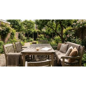 Houten tuintafel met boek en koffie in groene tuin